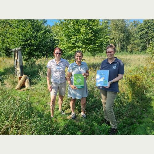 Viola Bödewadt (l.) und Christine Stecker (r.) überreichen Dr. Corinna zu Putlitz (M., Körber Technologies) das Siegel Kooperation Natur © A. Elatawna